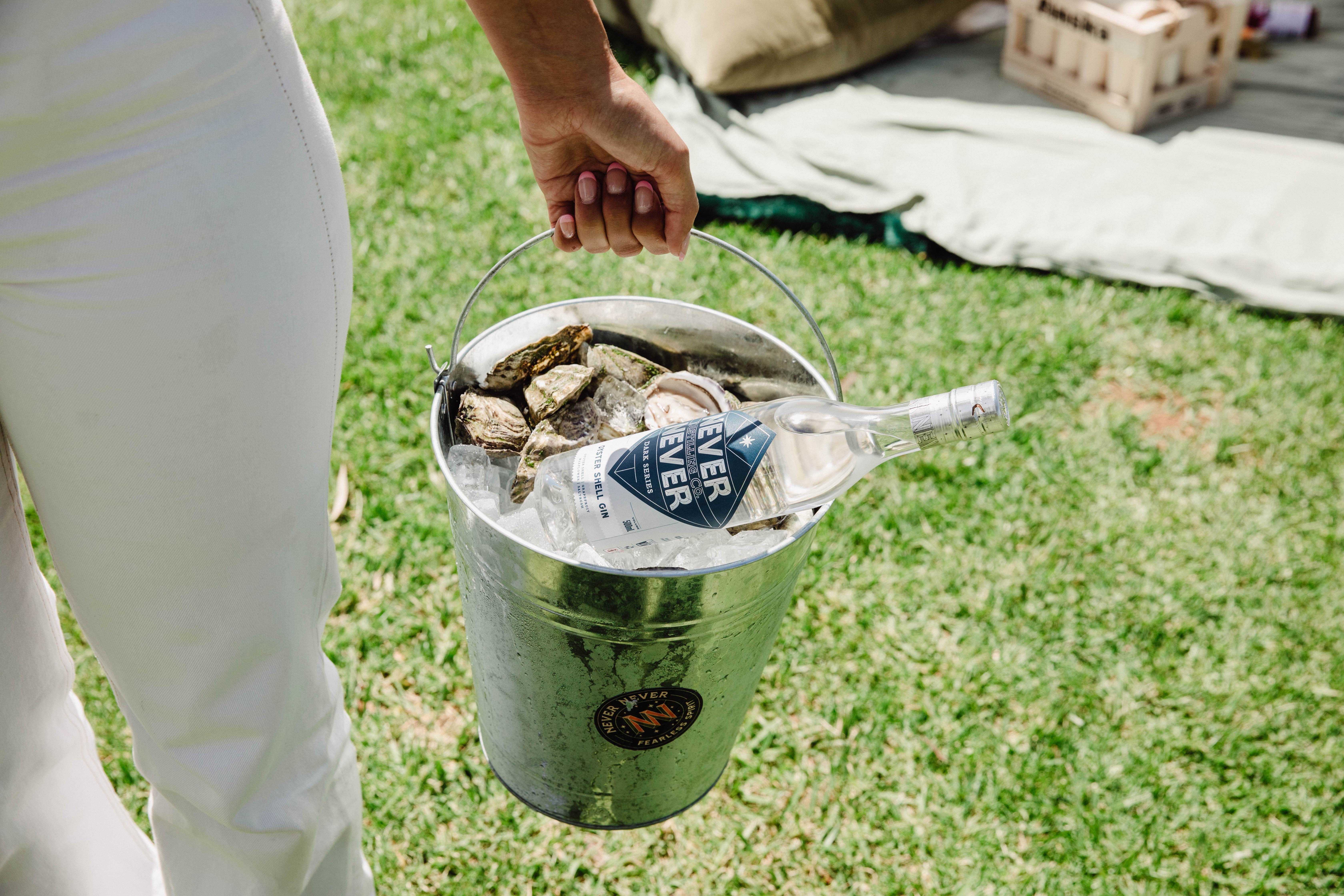 Never Never Oyster Shell Gin in bucket of Oysters being carried across lawn.
